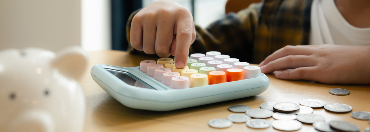 Kind telt muntgeld op rekenmachine uit spaarvarken